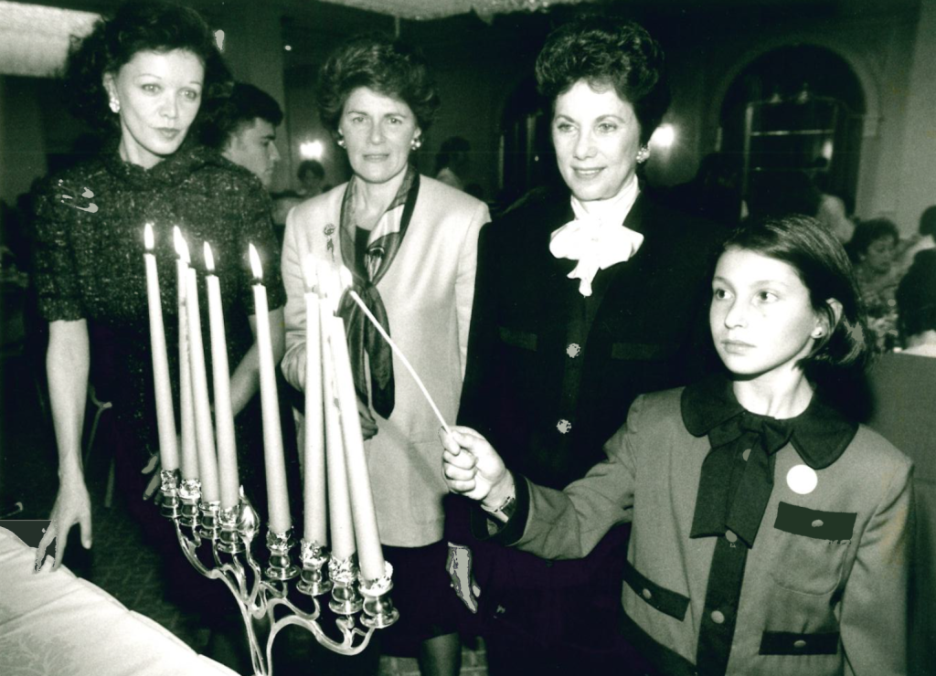 WIZO 75th Anniversary Luncheon at the Mayfair Hotel in 1993. L to R: Barbara Amiel, Ruth Sotnick Chair Michal Modai, and Luci Abraham lighting Chanukah candles
